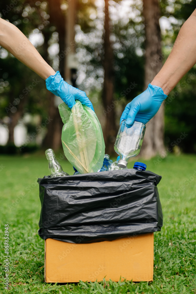 人们手持垃圾瓶，将塑料和玻璃放入回收袋。清理，污染，
