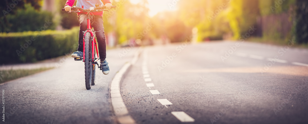 一个男孩骑着自行车在柏油路上的人行道上。