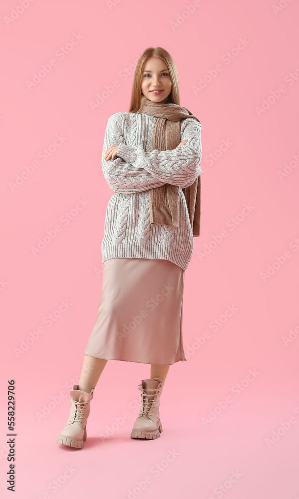 Young redhead woman in warm clothes on pink background
