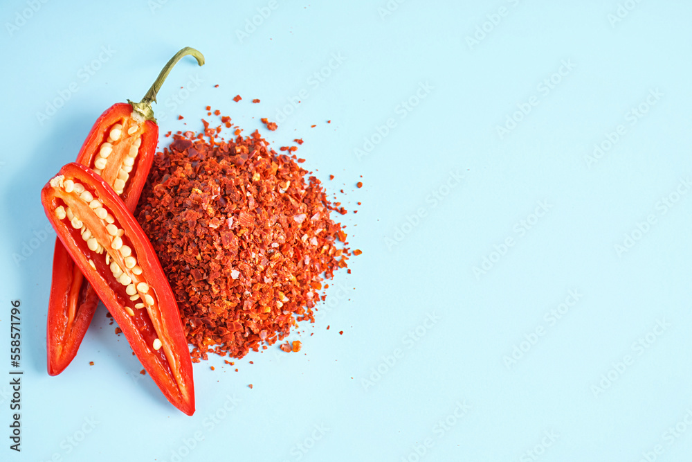 Heap of chipotle chili flakes and fresh jalapeno pepper on color background