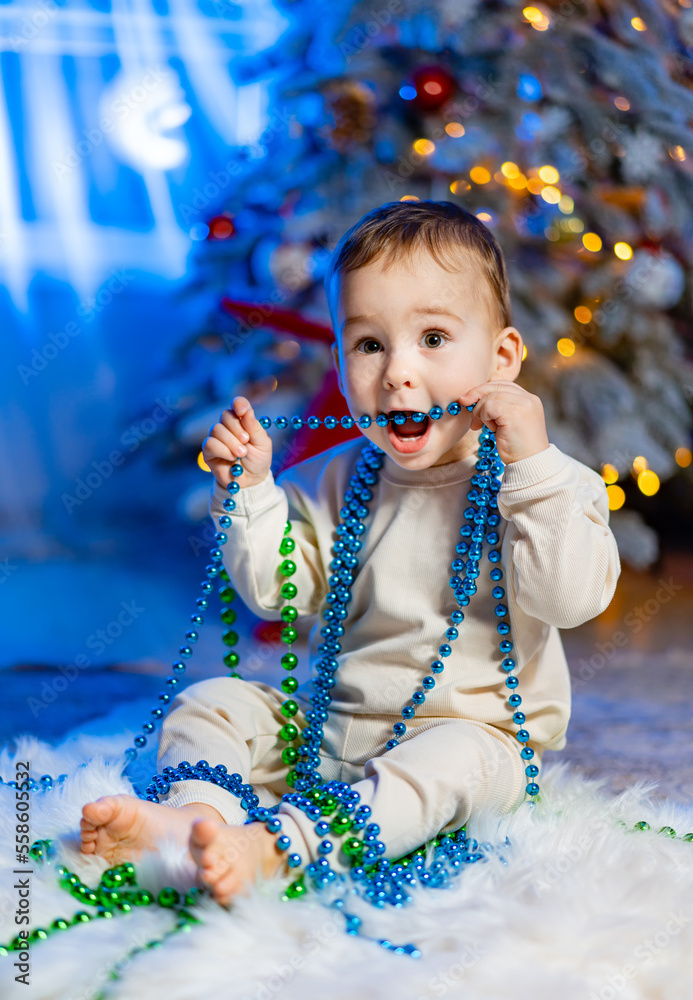 Happy little toddler boy playing near the Christmas tree. Merry Christmas and Happy Holidays!