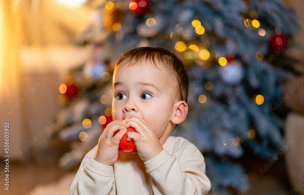 Merry Christmas! Happy little toddler boy playing near the Christmas tree. Lovely baby enjoy christm