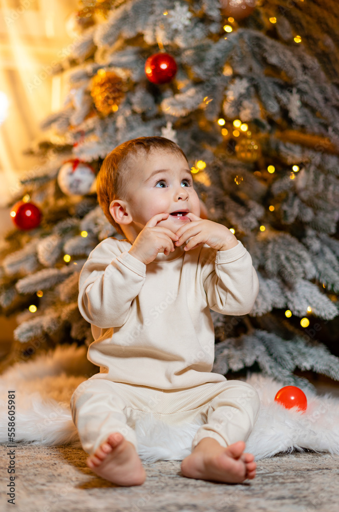圣诞快乐！快乐的蹒跚学步的小男孩在圣诞树旁玩耍。可爱的宝宝享受圣诞节