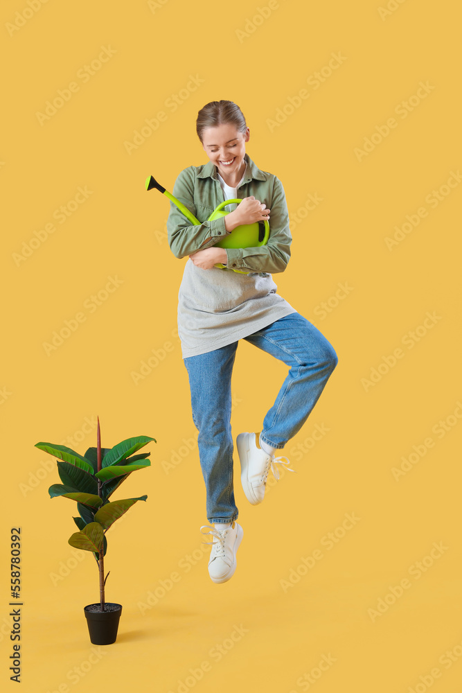 带喷壶和室内植物的女园丁在黄色背景上跳跃