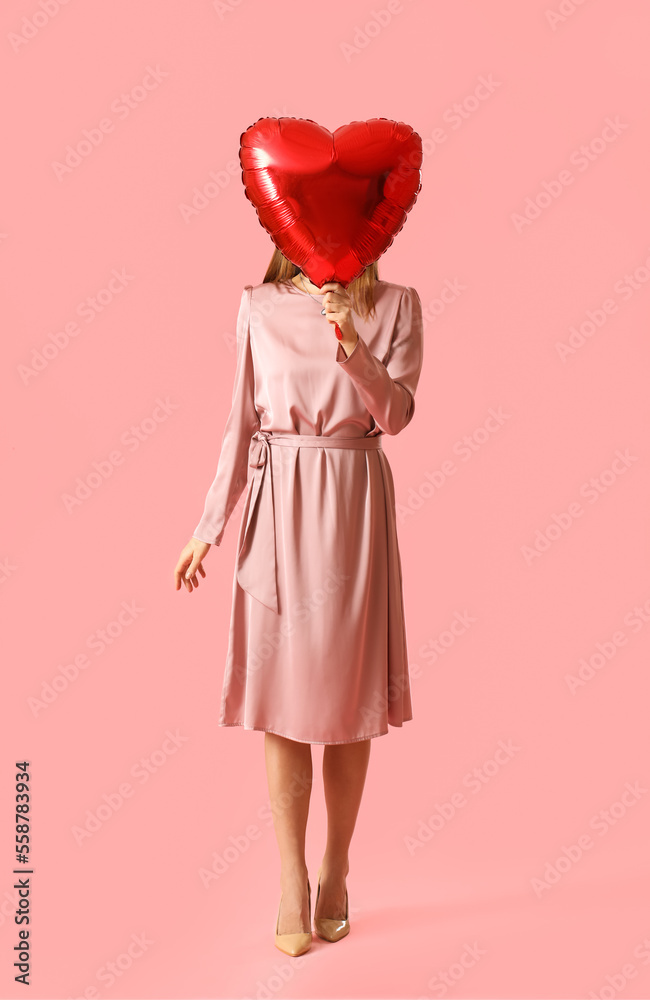 Young woman with balloon for Valentines Day on pink background