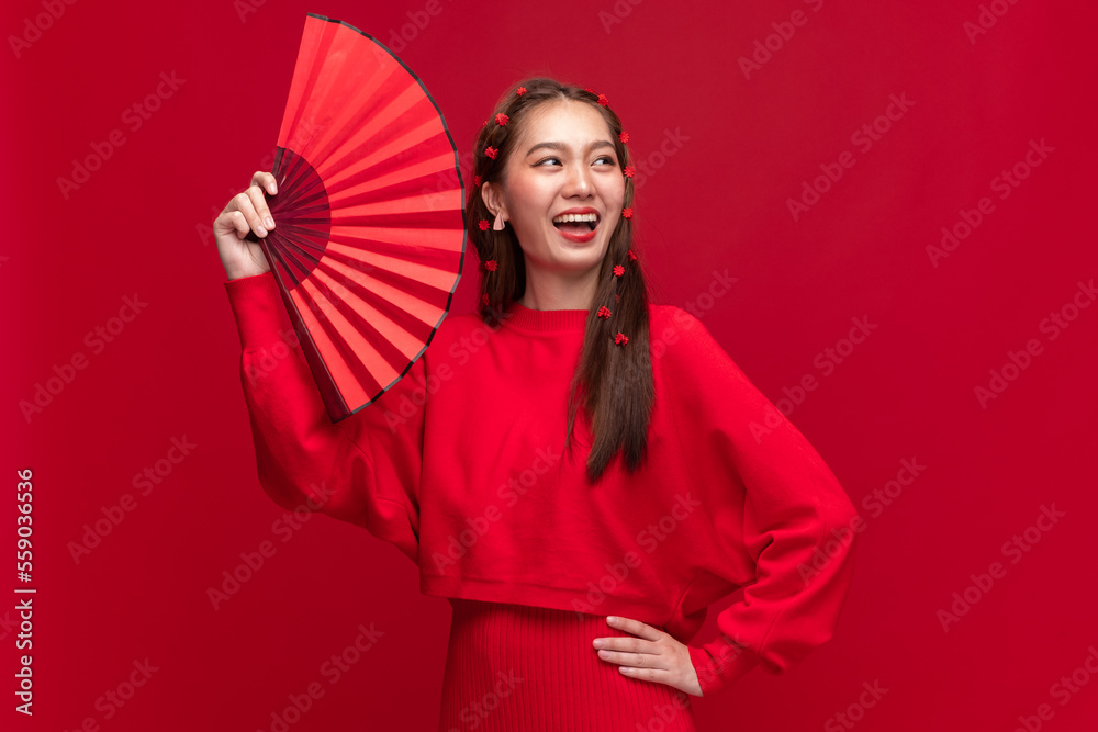 身穿红色毛衣连衣裙的亚洲年轻女子，红色背景为中国折扇