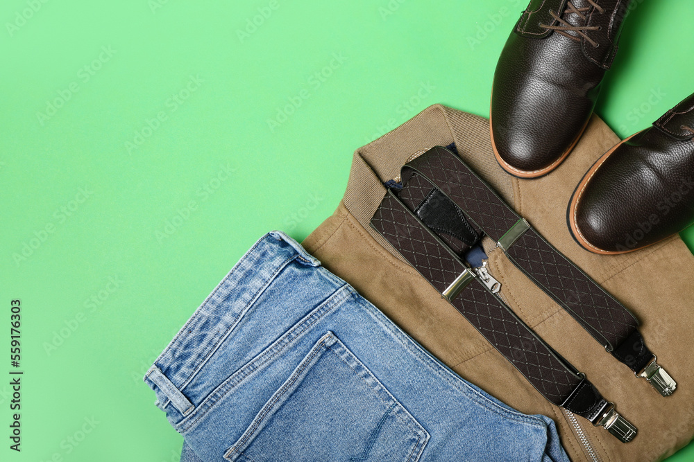 Male jeans, jacket, shoes and suspenders on green background, closeup