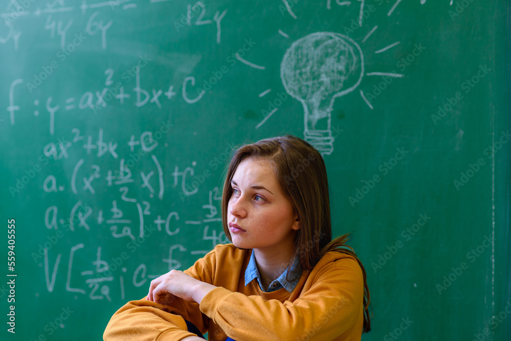 数学课上的十几岁女孩被数学公式淹没了。压力、教育、成功的概念。
