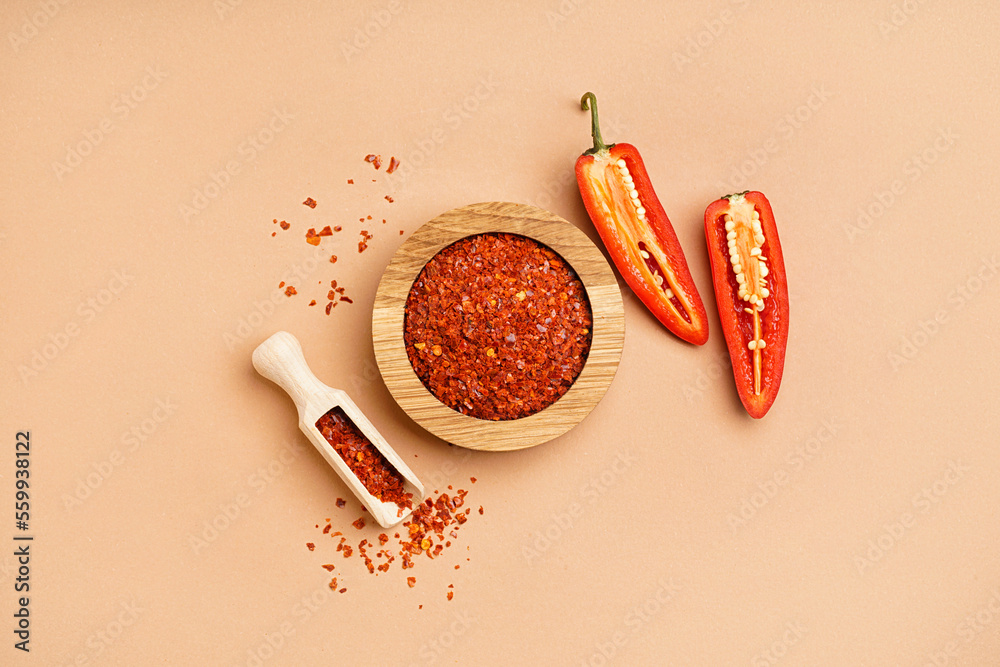 Bowl and scoop of chipotle chili flakes on color background