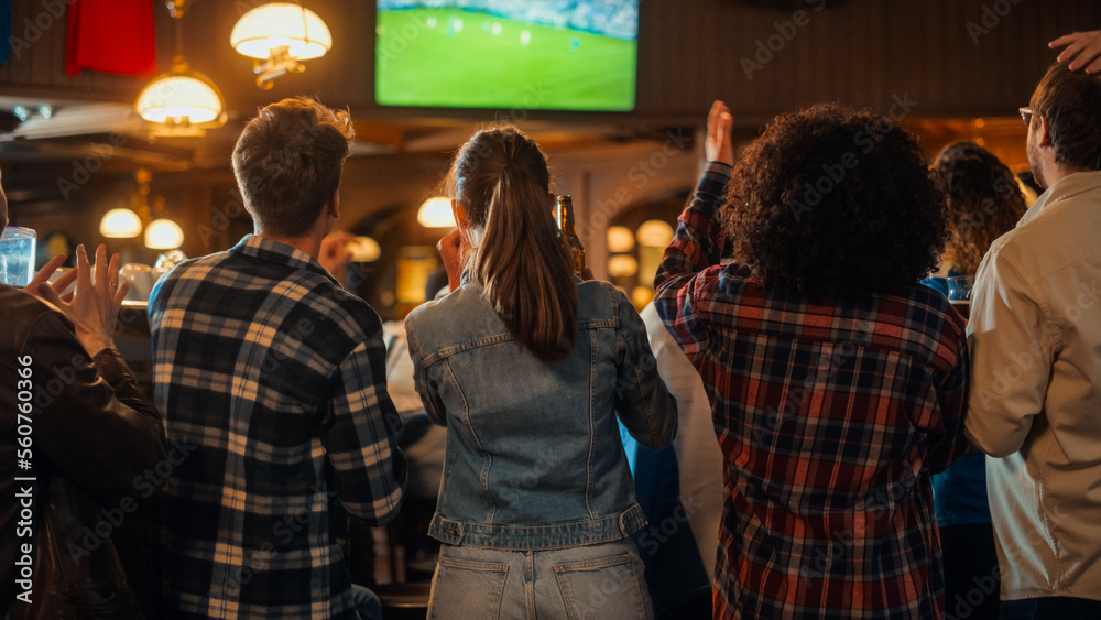 一群球迷在体育酒吧观看电视直播的足球比赛。人们欢呼