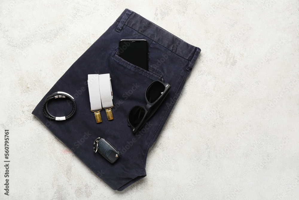 Male pants, accessories, mobile phone and car key on light background
