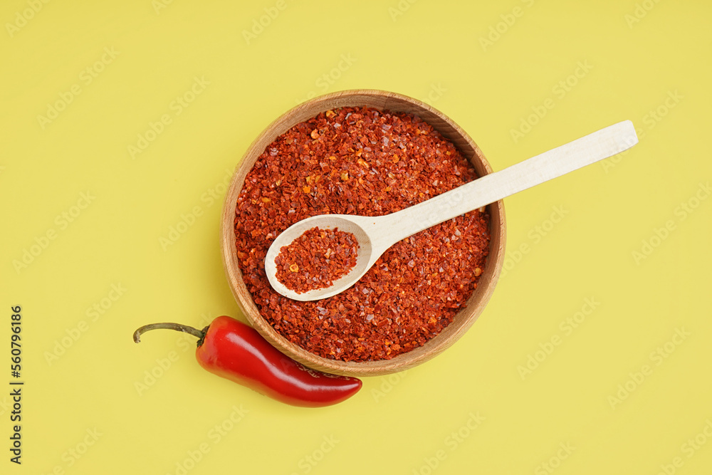 Bowl of chipotle chili flakes on yellow background