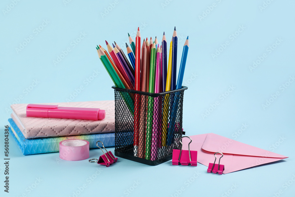 Holder with pencils, notebooks and stationery on blue background