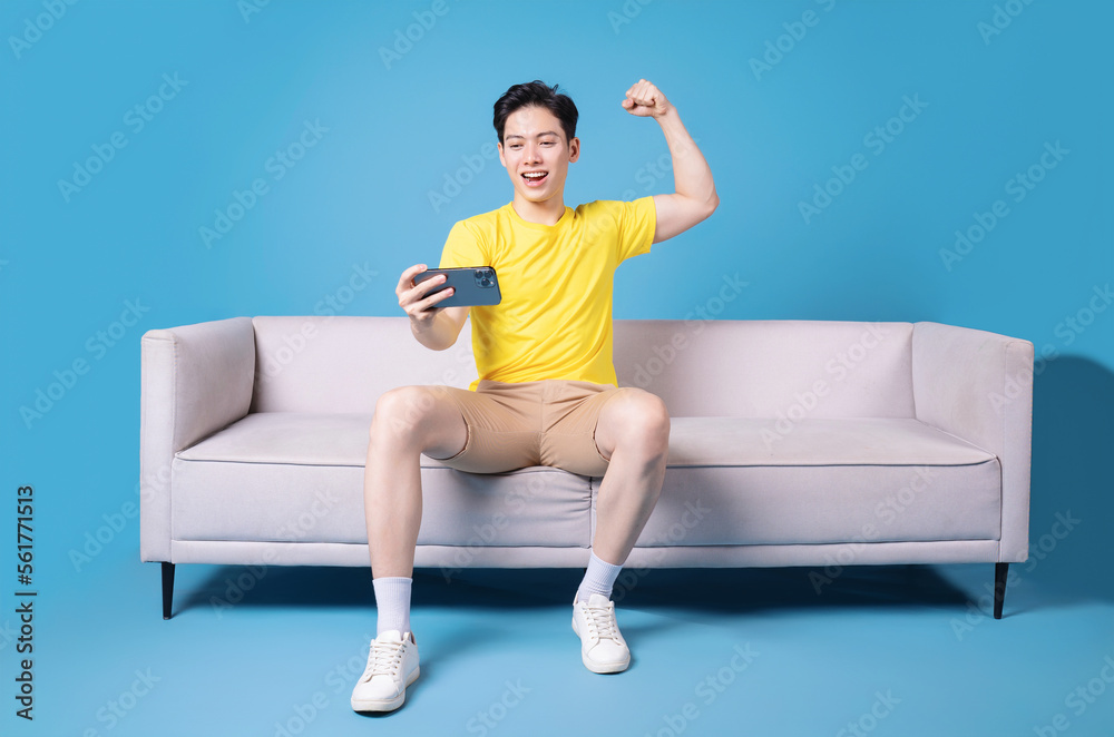 Image of young Asian man sitting on sofa