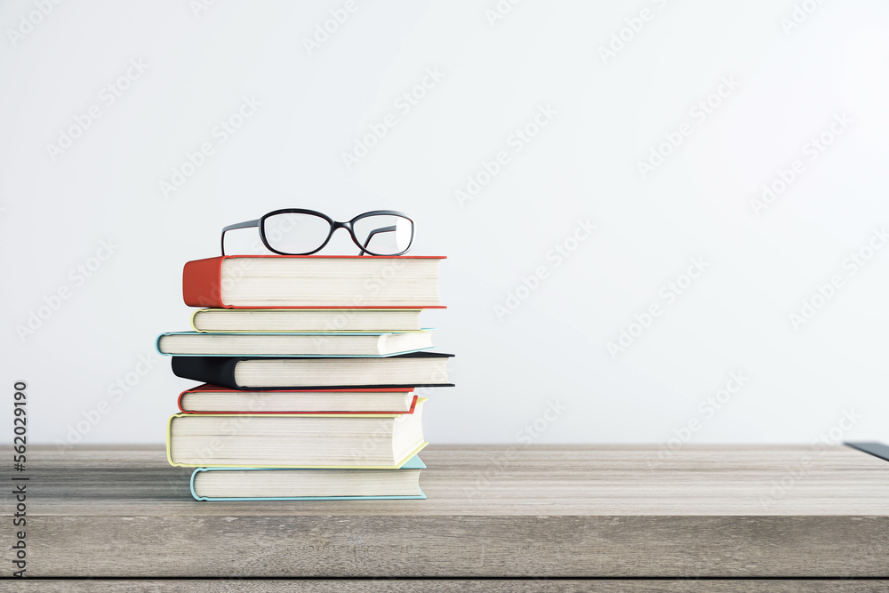 Education, personal development and study concept with eyeglasses on stack of books on wooden table 