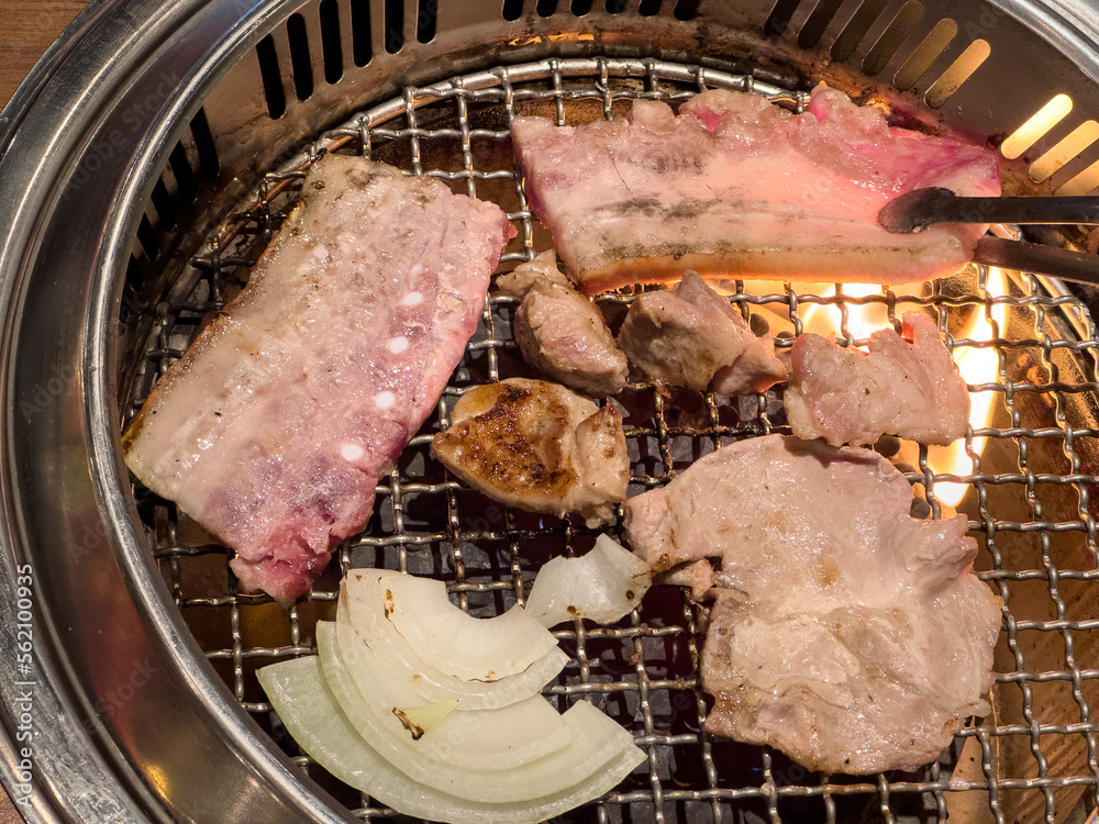 在餐厅用圆形烧烤网烧烤五花肉。
