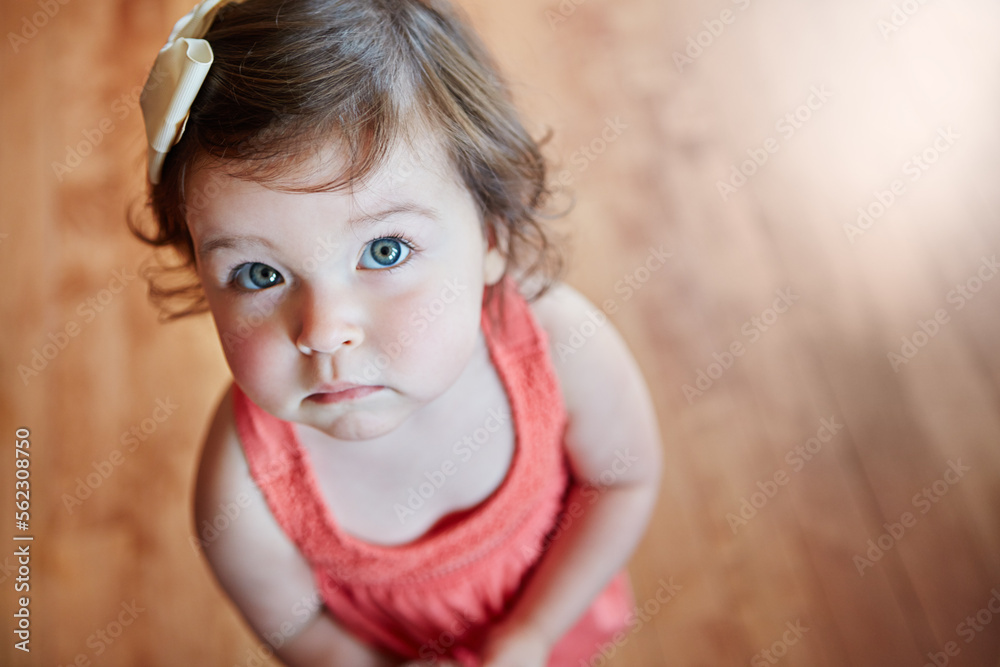 可爱、可爱的小女孩站在家里的木地板上，脸上露出甜蜜的表情。阿宝