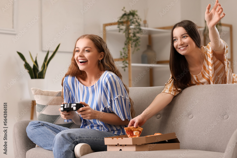 Young women with tasty pizza playing video game at home
