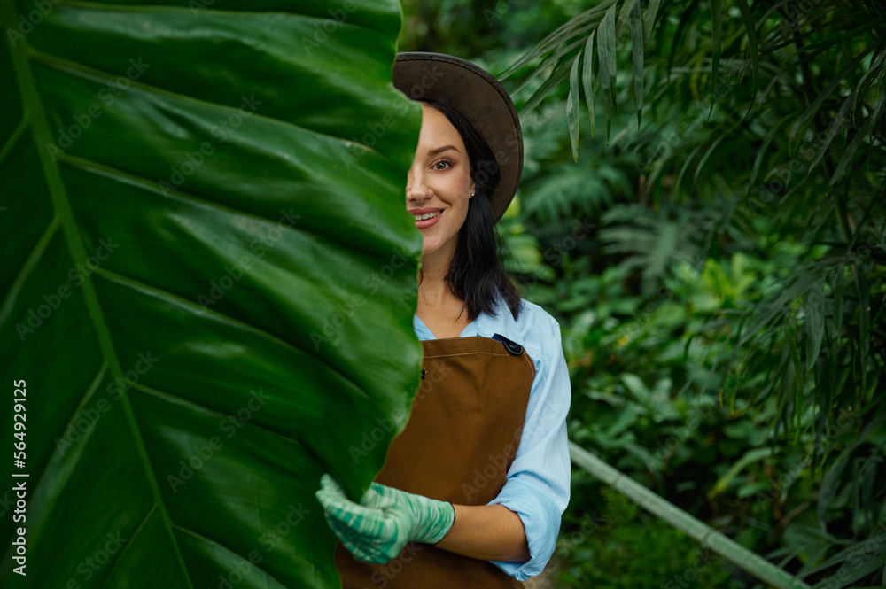 Portrait of beautiful woman gardener looking at camera through lush foliage