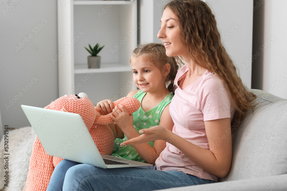 Little girl with toy and her mother having online psychologist session at home