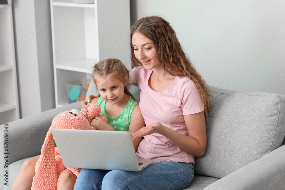 Little girl with toy and her mother having online psychologist session at home