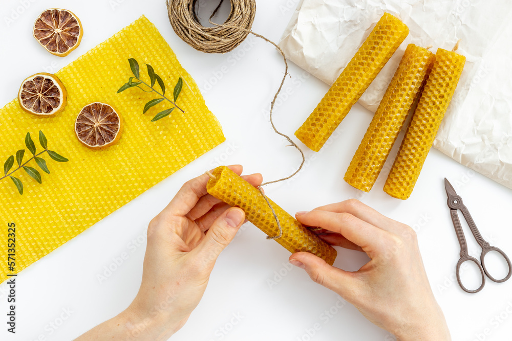 Hands making beeswax honey aroma candles with honeycombs, top view