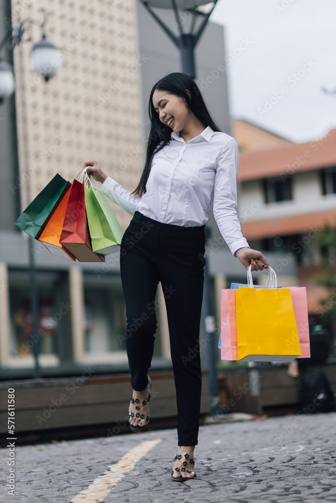 Cheerful and attractive young Asian woman carrying shopping bags. Female tourist carrying shopping b