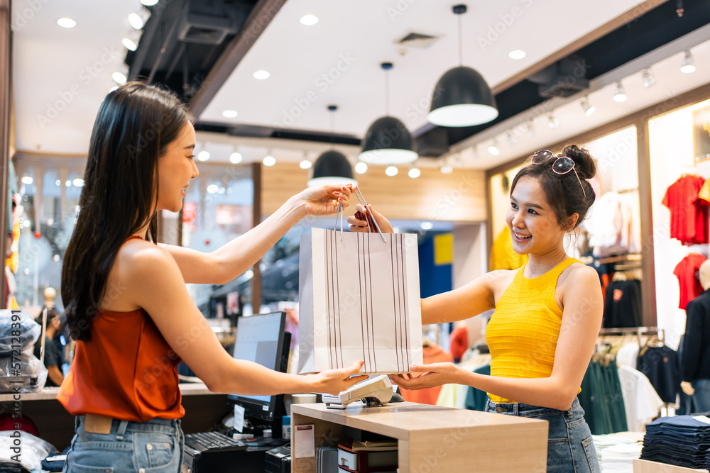 Asian young women purchasing clothes product in shopping mall center.