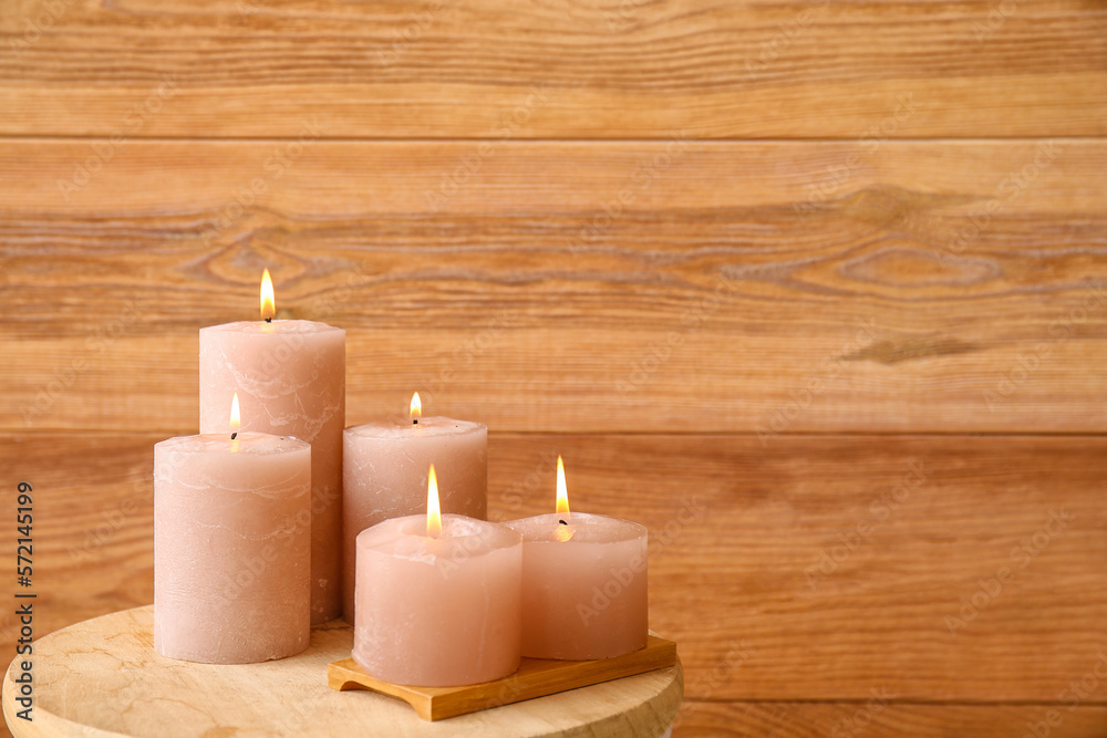 Burning candles on table near wooden wall