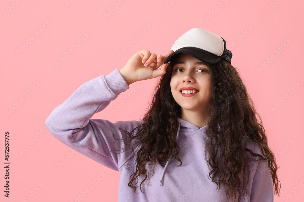 Teenage girl in cap on pink background