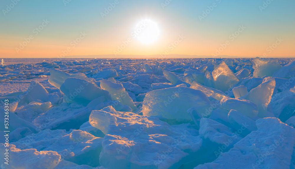 Beautiful winter landscape of frozen Lake Baikal at sunrise - Snowy ice hummocks with transparent bl