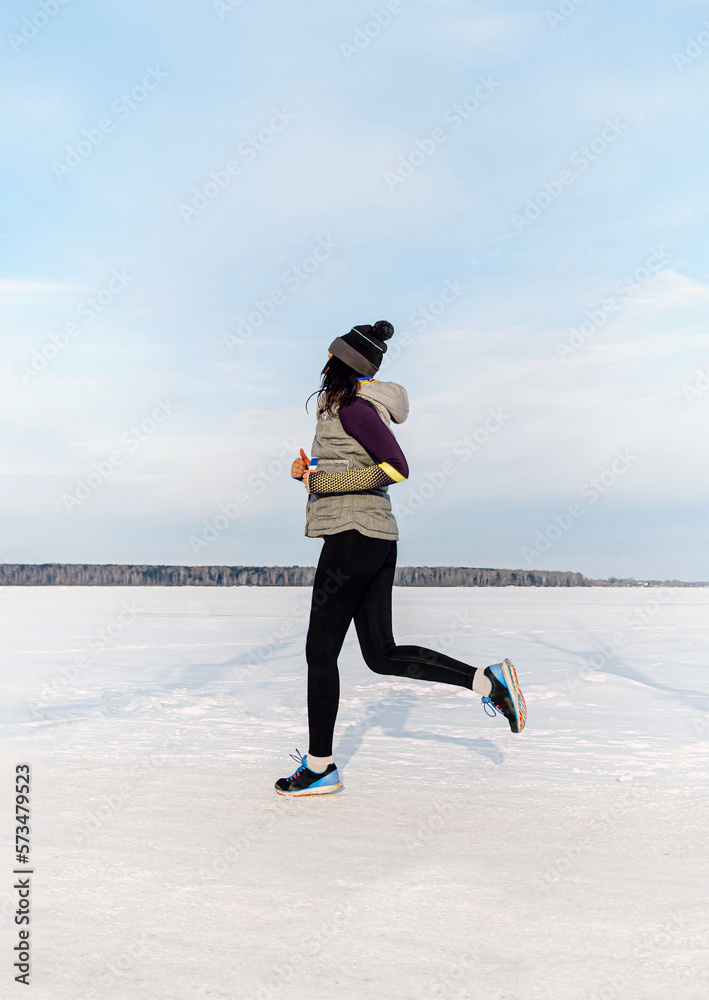 woman runner running snow field in winter trail marathon