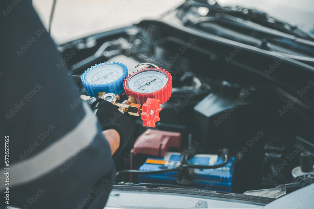 Close up hand of auto mechanic using measuring manifold gauge check the refrigerant and filling car 