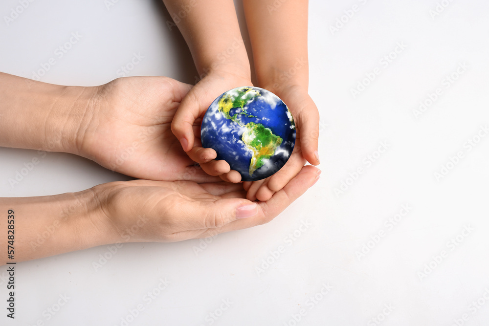 Hands of mother and child holding small planet Earth on white background