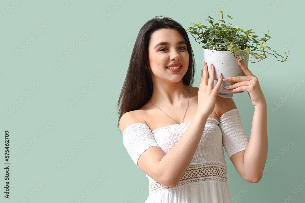 Young woman with houseplant on green background