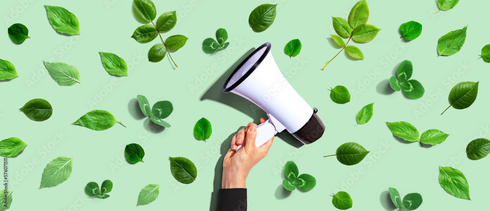 Person holding a megaphone with green leaves - flat lay