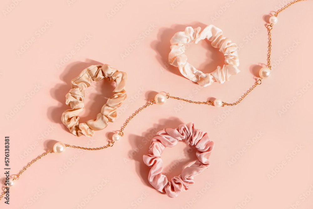 Silk scrunchies and necklace on pink background