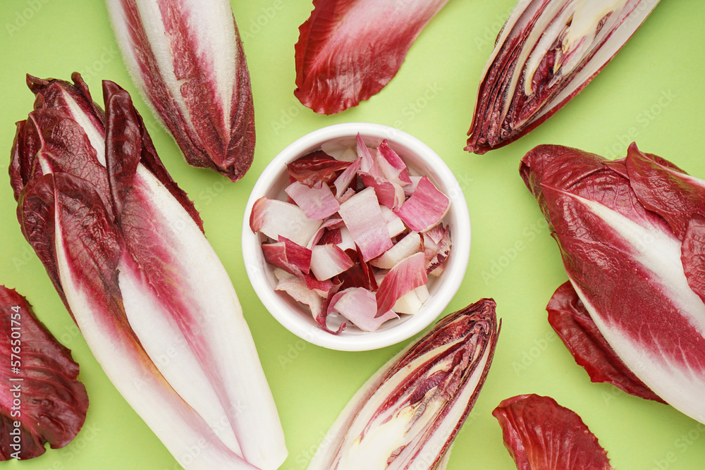 Composition with whole and cut red endive on green background, closeup