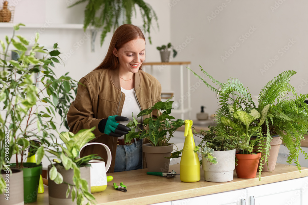 Young woman with green houseplants on table at home