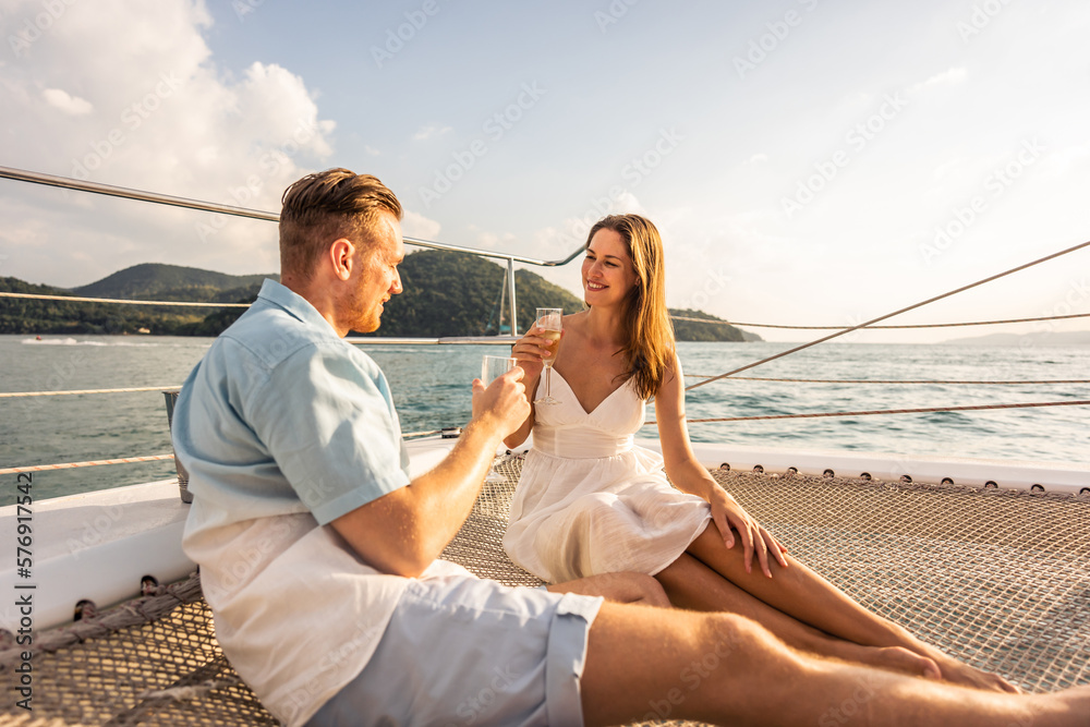 Caucasian young couple drinking champagne while having party in yacht. Attractive man and woman hang