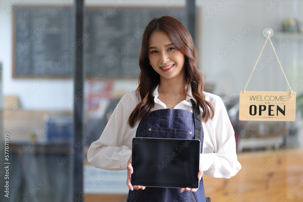 Portrait of a young female entrepreneur hanging a welcome sign in front of a coffee shop. Beautiful 