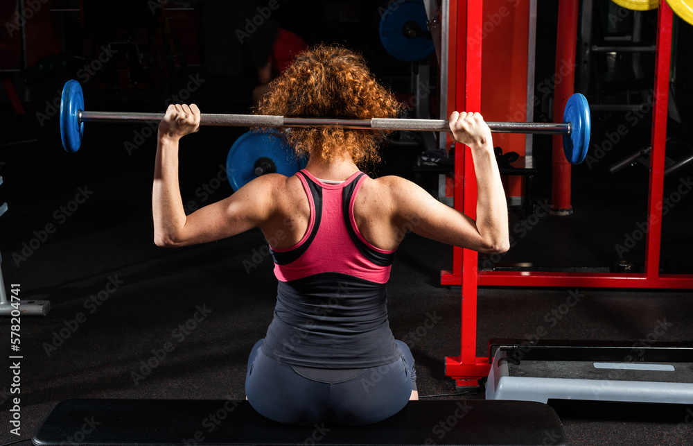 Woman bodybuilder engaged with a barbell in the gym