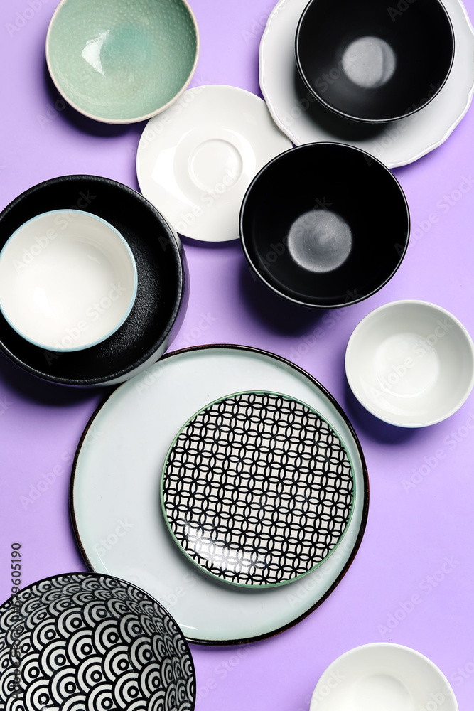 Composition with clean ceramic plates and bowls on lilac background