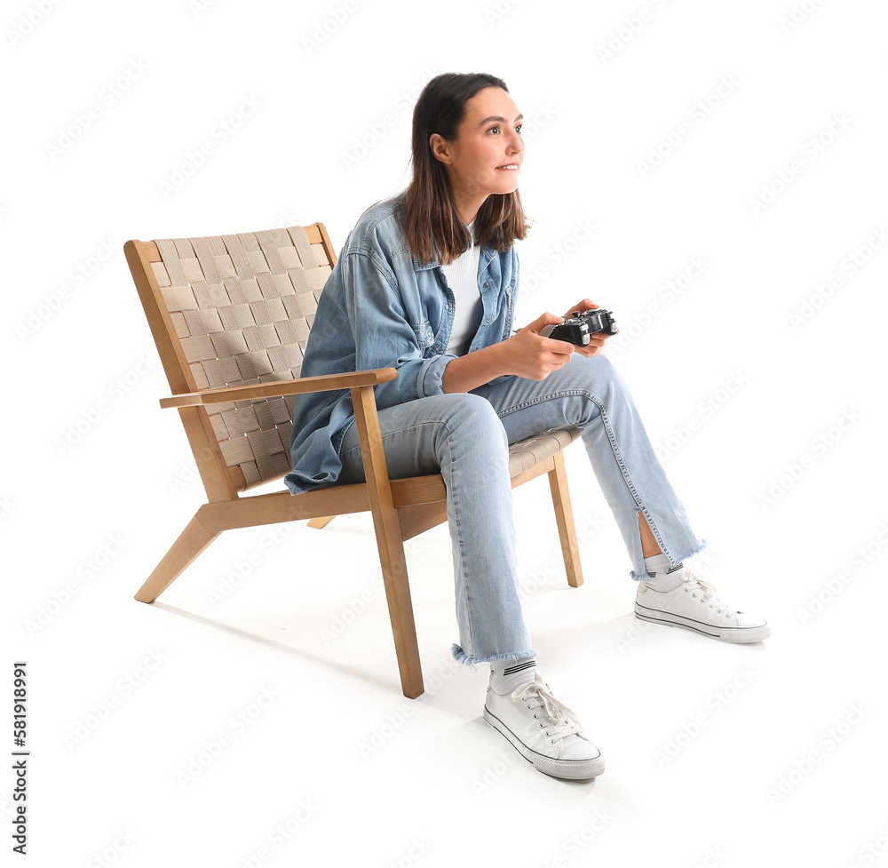 Young woman playing video game in wooden armchair on white background