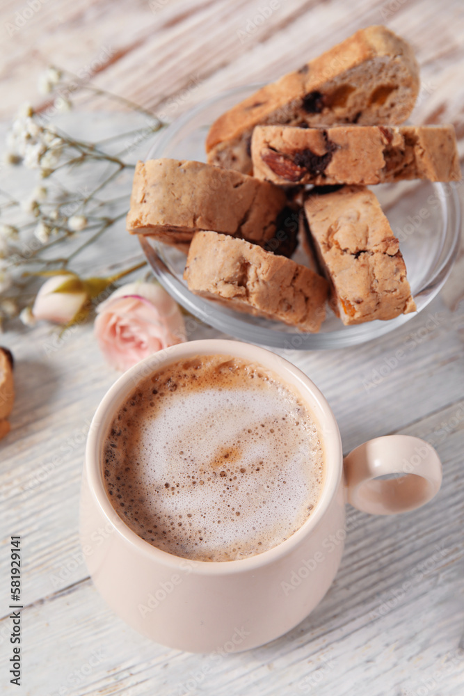 Board with cup of coffee and delicious biscotti cookies on white wooden background