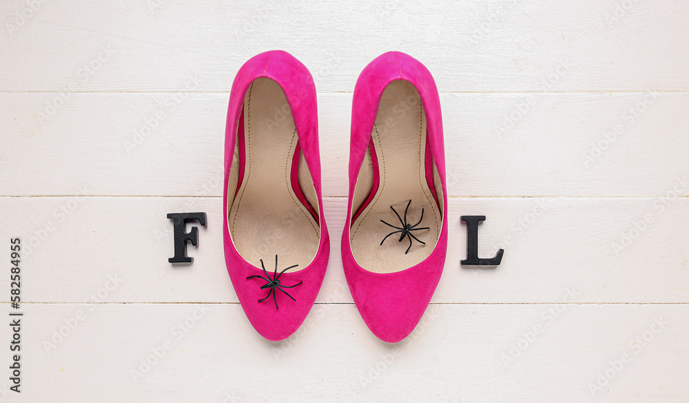 Word FOOL with female shoes and spiders on white wooden background