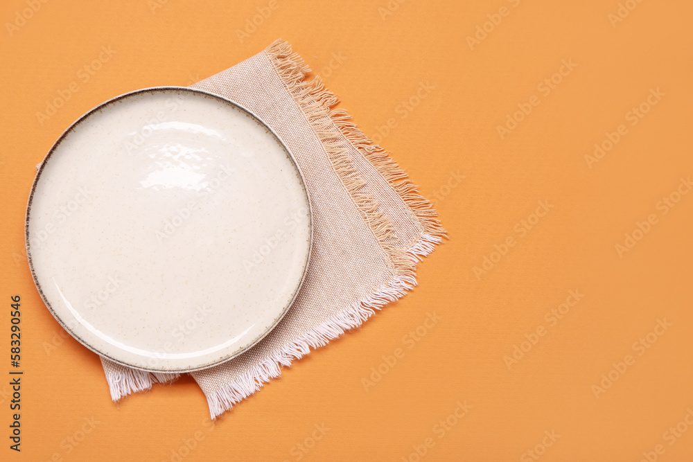 Empty plate with napkin on color background