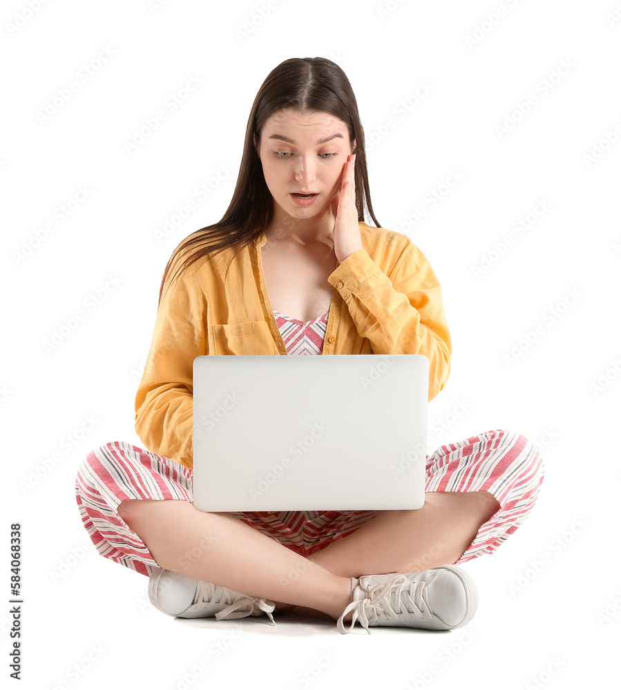 Surprised young woman with laptop sitting against white background