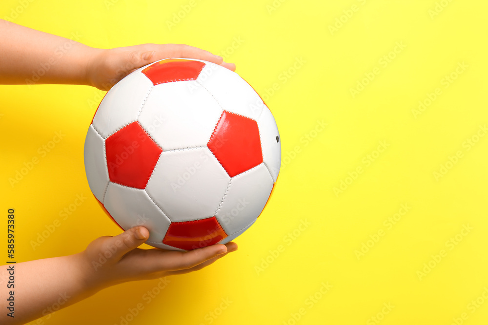 Hands with soccer ball on yellow background