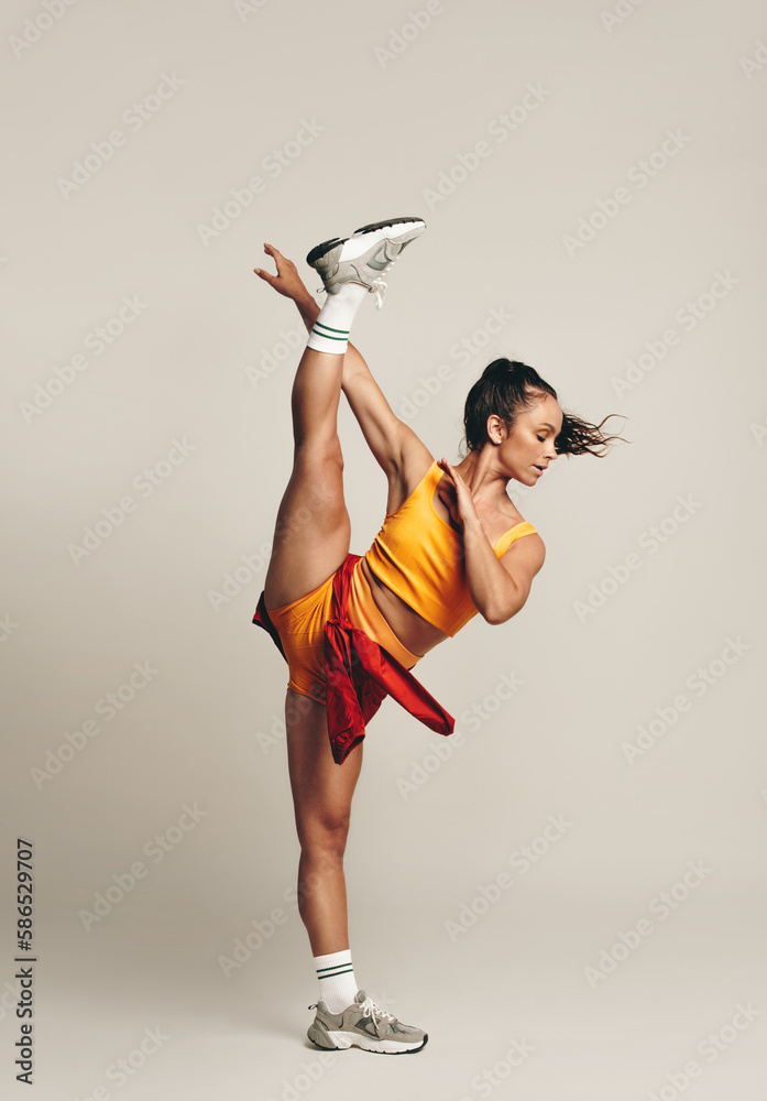Fit young woman doing a one-legged gymnastic workout in a studio